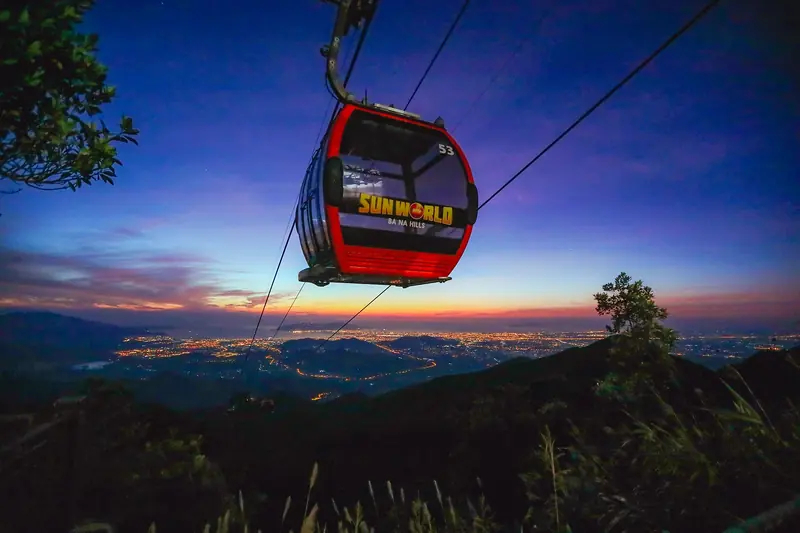 A Bà Nà Hills cable car cabin against a twilight sky, city lights far below