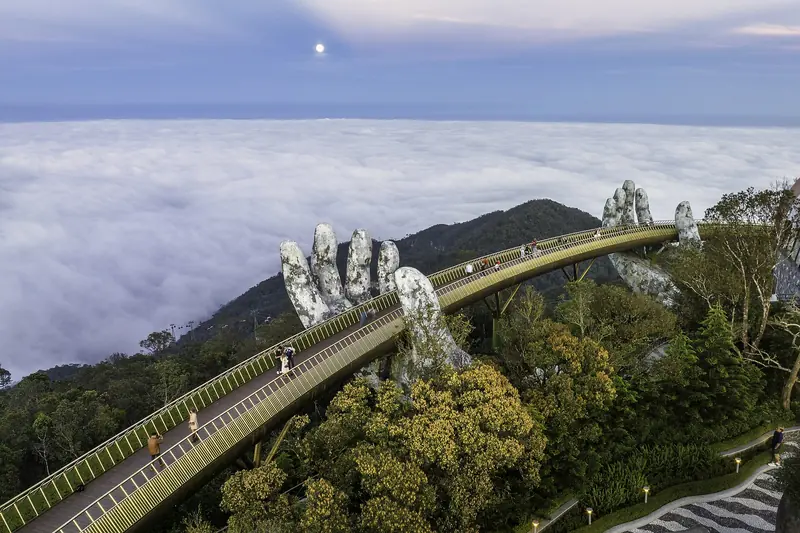 Aerial view of the Golden Bridge and its giant stone hands above a sea of clouds