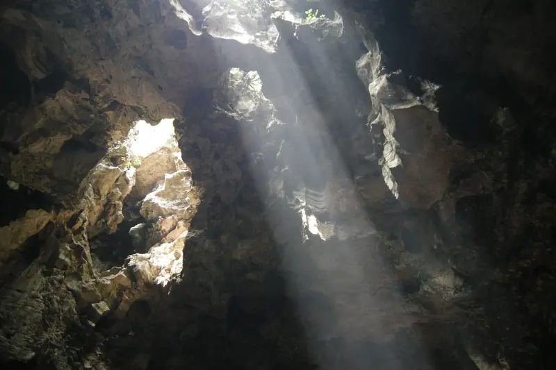 Shafts of sunlight piercing the roof of Huyền Không Cave