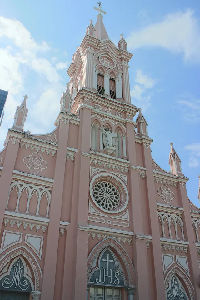 The pink Gothic façade and spire of Da Nang Cathedral under a blue sky