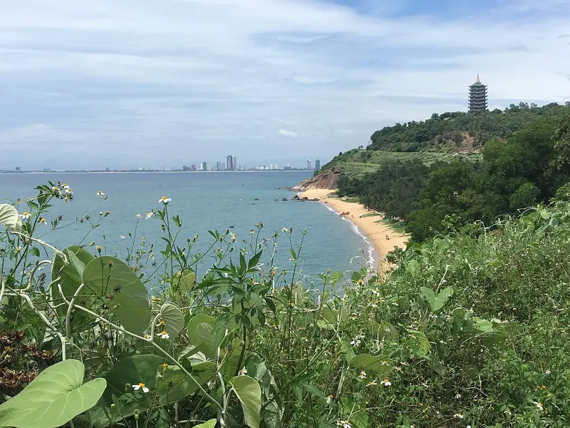 View from the Sơn Trà Peninsula over a curving beach towards Da Nang, with the Linh Ứng Pagoda tower on the headland